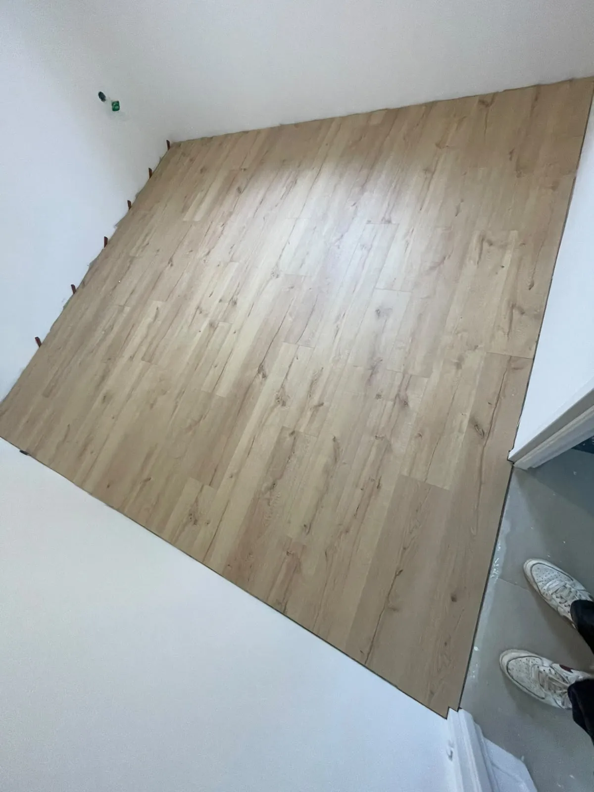 Parquet flottant en cours de finition, cales de dilatation le long des murs
