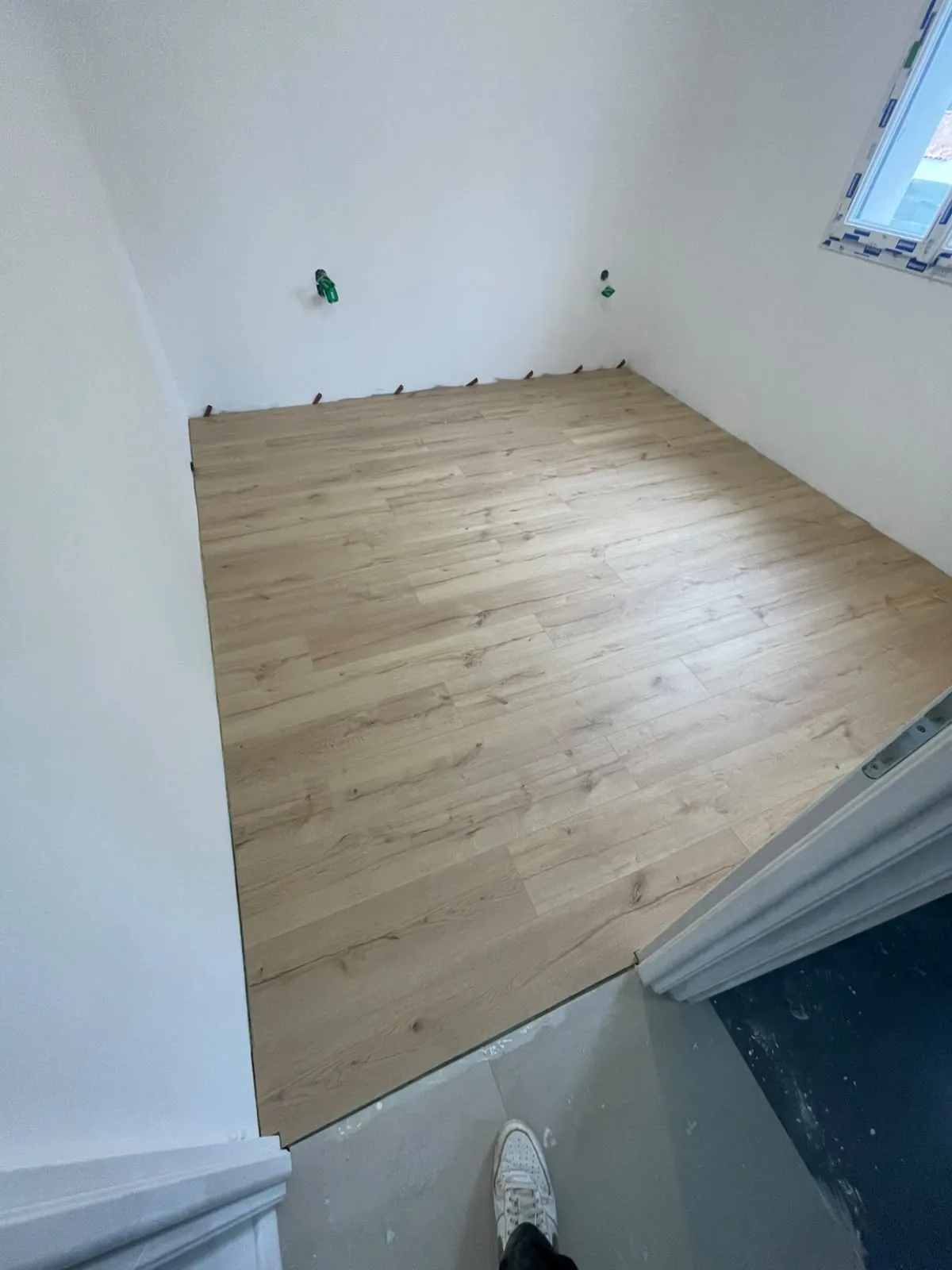 Parquet flottant dans une chambre neuve, jonction nette avec le carrelage du couloir